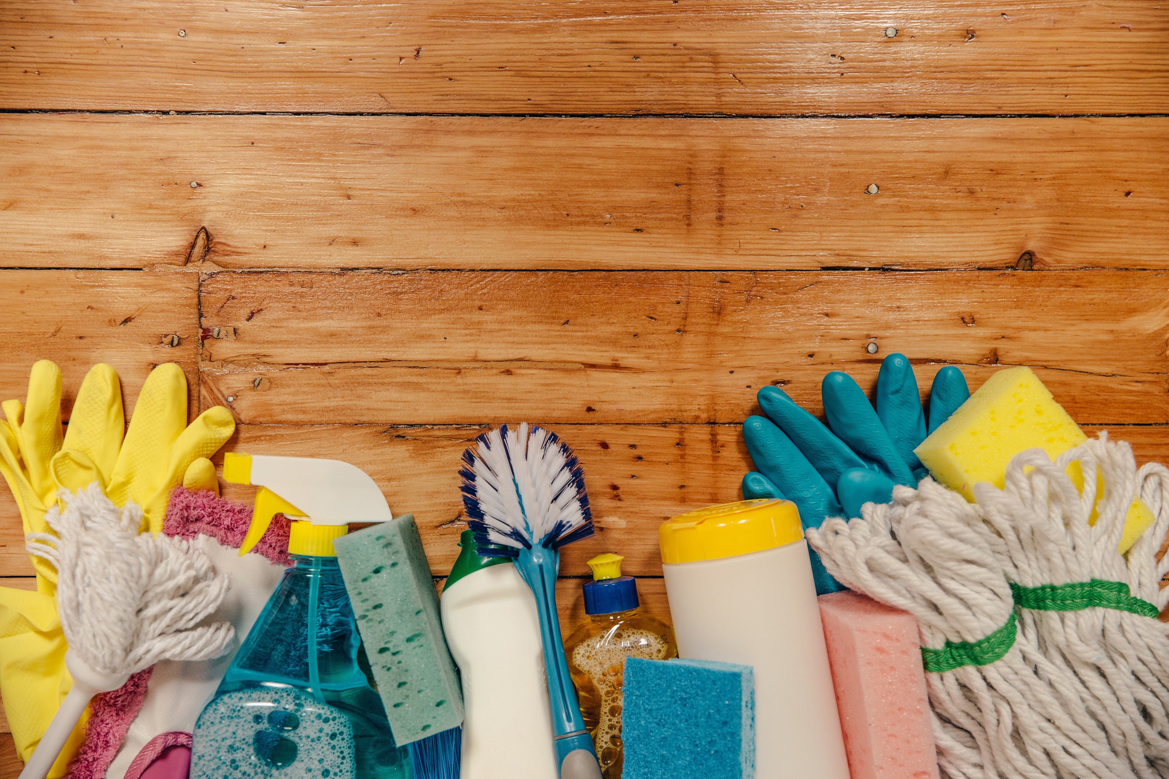 eco friendly Sapphire Cleaning supplies including sponges, bottles, and gloves on a wooden surface
